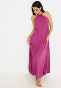 Vestido maxi en un vibrante fucsia, diseño de cuello halter, tejido ligero, silueta fluida, textura suave, que llega hasta los tobillos.