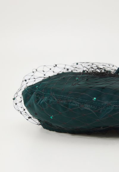 Türkiis satiinberett musta võrgukihtiga, millel on väikesed rohelised kaunistused, ümar, pehme kuju ja sile tekstuur.