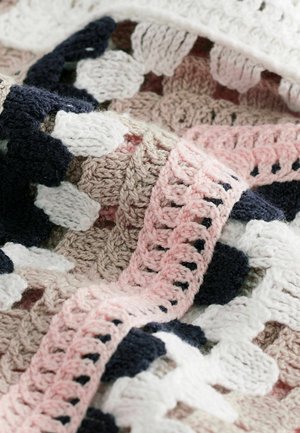Gehaakte deken met een herhalend patroon van roze, marineblauwe, witte en beige garens met getextureerde steken en gegolfde randen.