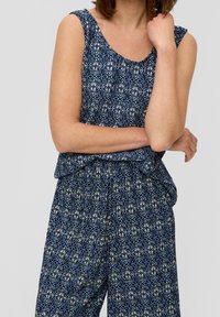 Haut sans manches à motifs bleus et pantalon assorti en tissu léger ; présente des designs géométriques floraux en blanc avec des accents jaunes.