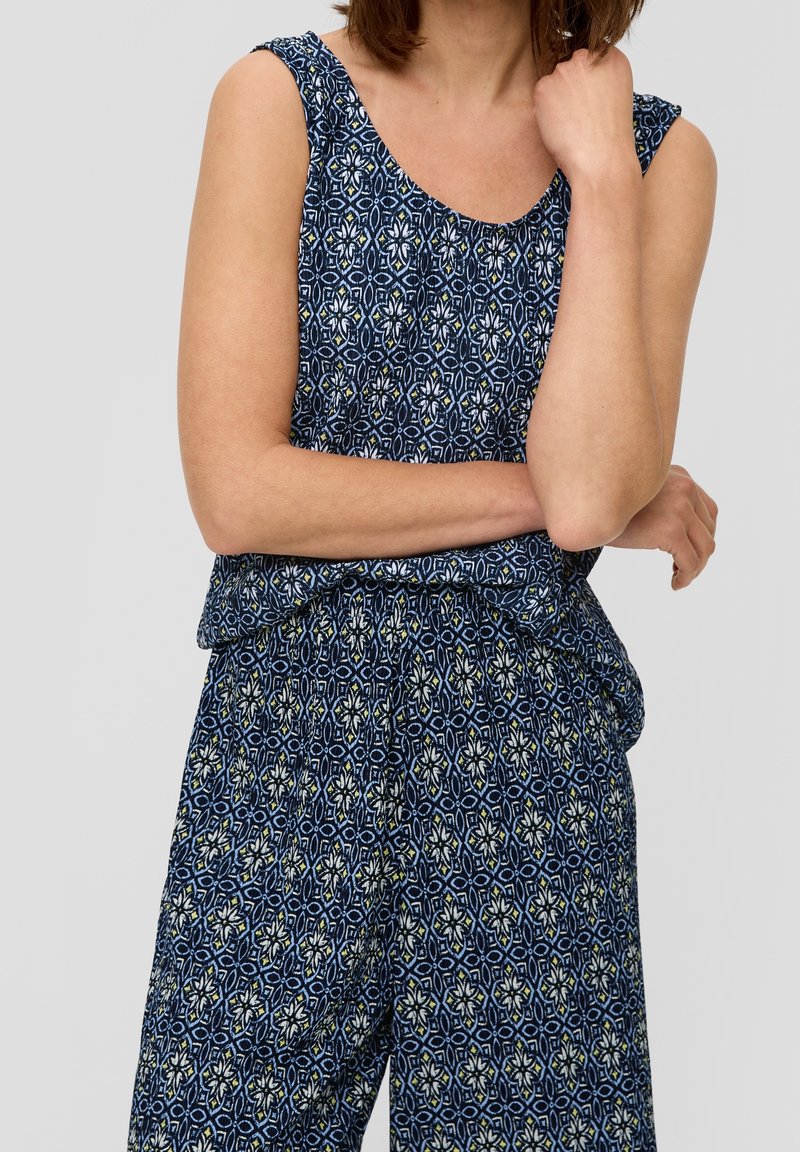 Haut sans manches à motifs bleus et pantalon assorti en tissu léger ; présente des designs géométriques floraux en blanc avec des accents jaunes.