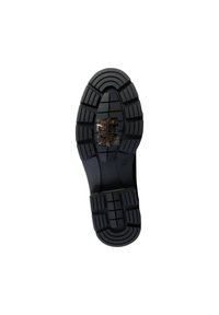 Black rubber shoe sole featuring a patterned tread design, multiple raised sections, and a transparent label with care symbols.
