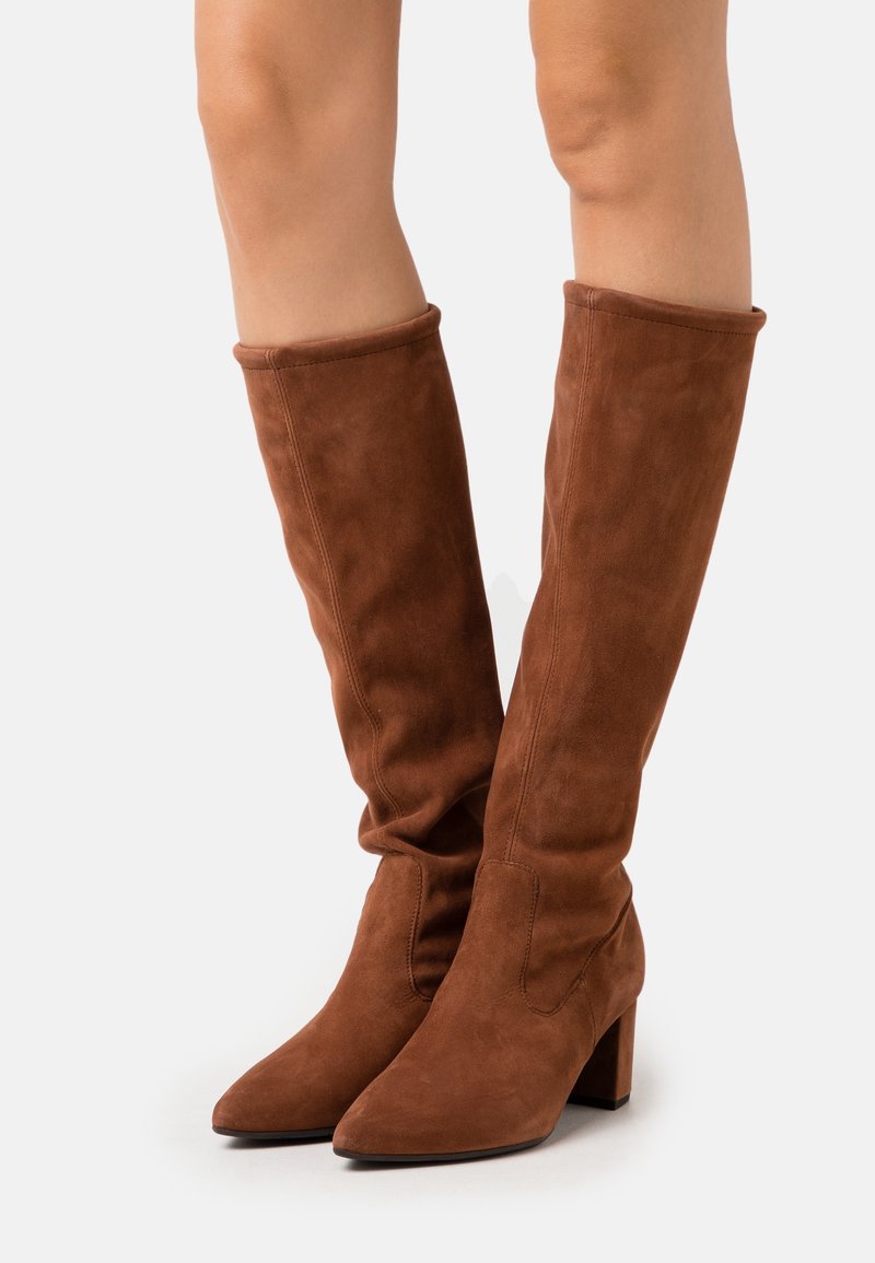 Bottes en suède marron hauteur genou avec un bout pointu et un talon bloc. Le design présente une texture flasque et un détail de couture minimal.