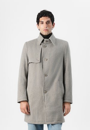 Grau Wollmantel mit hohem Kragen, vorderen Knöpfen und seitlichen Taschen. Besitzt eine Klappe über einer Schulter und eine gerade Silhouette.