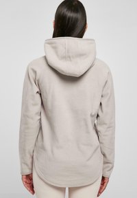 Lys grå fleece hoodie med en afslappet pasform, hætte og rund kant. Har lange ærmer og et blødt, tekstureret stof.