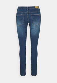 Jeans skinny de mezclilla azul con un lavado desvanecido, con una cintura de talle medio y dos bolsillos traseros. La tela parece suave y resistente.