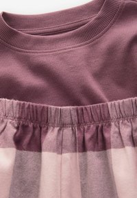 Top ribbato di color mauve abbinato a una gonna a quadri rosa chiaro e mauve con tessuto morbido e vita elasticizzata.