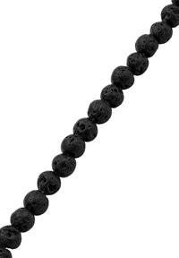 Rad av små, runda svarta vulkaniska lavapärlor med porös textur på en vit bakgrund.
