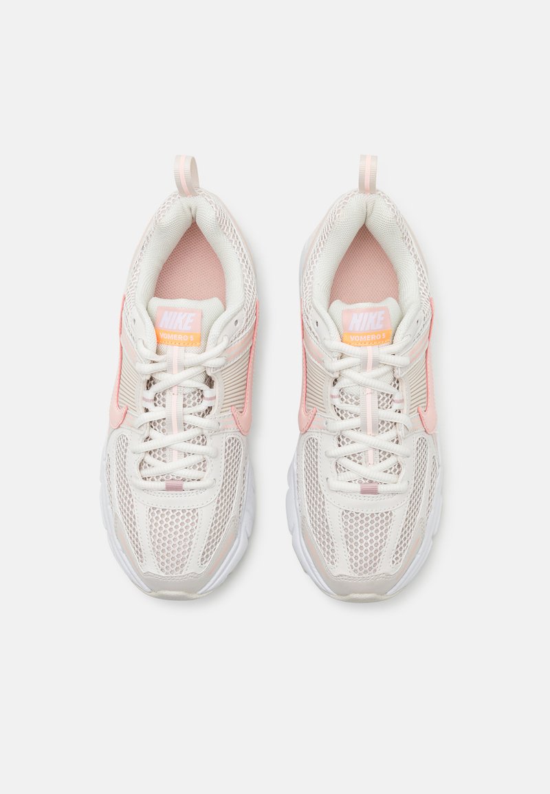 Nike Vomero 5 sneakers, met een bovenwerk van wit en lichtroze mesh, een gepolsterde kraag en een witte zool met gestructureerde accenten en vetersluiting.
