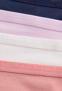 Quattro pezzi di tessuto lavorato a maglia piegati in blu navy, rosa chiaro, bianco e corallo, ognuno con una fascia in vita con la scritta "NEXT" in rilievo.
