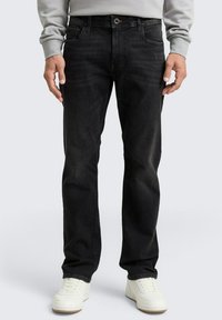 Jeans in denim neri con vestibilità dritta, design a cinque tasche, sbiadimento sottile e passanti per cintura, abbinati a sneakers bianche.