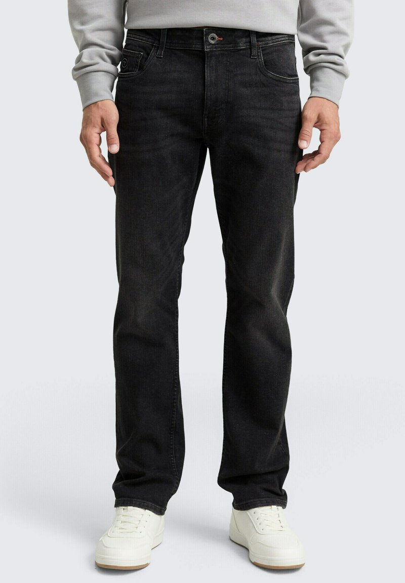 Jeans in denim neri con vestibilità dritta, design a cinque tasche, sbiadimento sottile e passanti per cintura, abbinati a sneakers bianche.