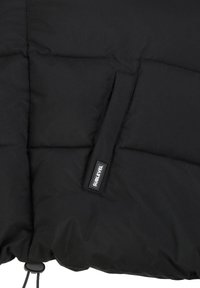 Schwarze gepolsterte Jacke mit glatter Textur, strukturiertem Steppmuster und einer Seitentasche mit einem Etikett, das "SUBLEVEL" liest.