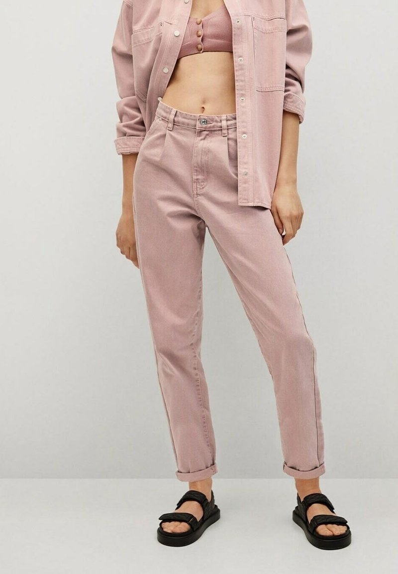 Pantalones de mezclilla rosas con un corte relajado, que presentan un cierre de botones y puños enrollados, combinados con una camisa corta abotonada a juego. Sandalias negras.