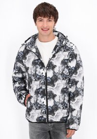 Giacca con cappuccio caratterizzata da un design astratto a spirale in bianco e nero, realizzata in tessuto leggero. Presenta una zip frontale e due tasche laterali.