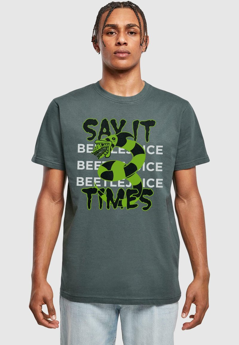 Donkergrijze katoenen t-shirt met de tekst "SAY IT BEETLEJUICE" in zwart en groen, vergezeld van een afbeelding van een groene slang en monsterontwerp.