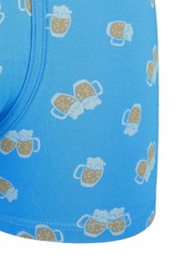 Niebieskie elastyczne slipy z wzorem powtarzających się kufli piwa z pieniującą się górą. Gładka tekstura i szczegóły elastycznego paska.