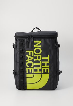 Sac à dos noir en matériau durable avec un logo jaune bien visible. Il comprend une fermeture éclair, des bretelles réglables et des accents sur les côtés.