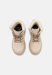 Lys beige støvler laget av glatt lær med kunstpelsforing, metalliske snøringer og grå lisser, med en robust såle og rund tå.
