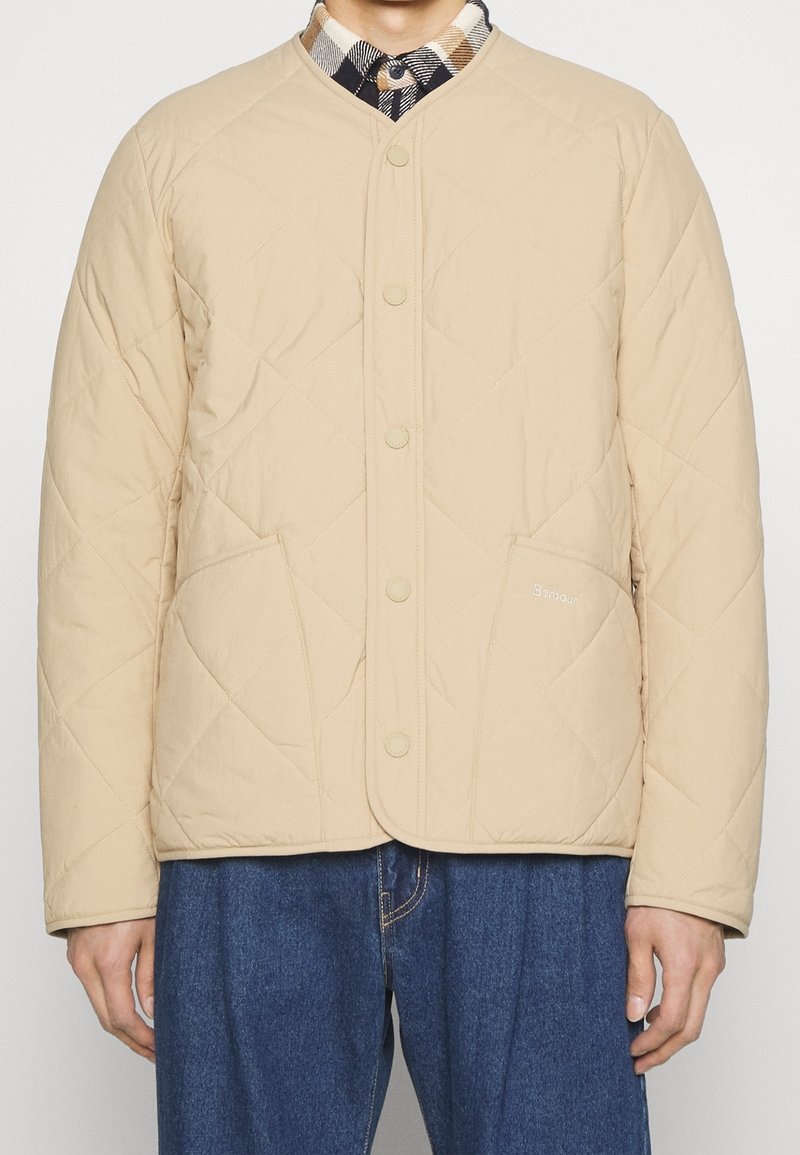 Beige Steppjacke mit rundem Ausschnitt, Druckknopfverschluss und Vordertaschen. Leichter Stoff mit subtiler Textur.