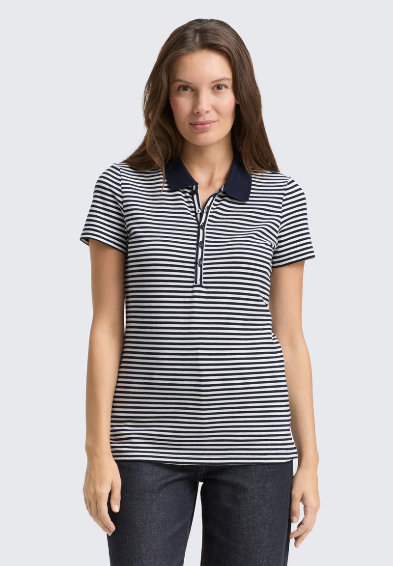 Marineblå og hvid stribet polo skjorte med korte ærmer og krave; har en knaplukning. Bæres med mørke denim bukser.