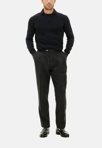 Marineblaues strukturiertes Strickoberteil mit Kragen, kombiniert mit einer hoch taillierten schwarzen Leinenhose. Das Schuhwerk sind schwarze Lederloafer.
