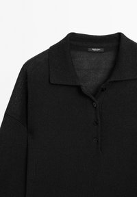 Black knit long-sleeve polo shirt with a collar and three buttons, featuring a textured fabric and a label at the neckline.