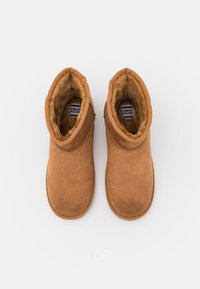 Brune semskede ankelstøvler med blødt uldfor, rund tå og enkle stikning detaljer. Har et lavt profil design for let påklædning.