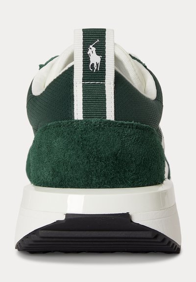 Τακούνι αθλητικού παπουτσιού από σκούρο πράσινο σουέντ και ύφασμα με λευκή και μαύρη σόλα, με λευκό λογότυπο παίκτη πόλο σε κατακόρυφη πράσινη και λευκή λωρίδα.