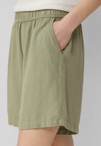 Szorty do kolan w kolorze oliwkowym wykonane z lekkiego materiału. Posiadają elastyczny pas i boczne kieszenie, z subtelnym detalem z logo.