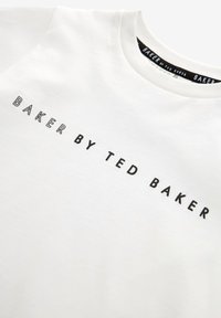 Biała bawełniana koszulka z napisem "BAKER BY TED BAKER" w czarnym, pogrubionym kroju na piersi, z klasycznym okrągłym dekoltem.