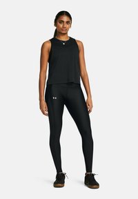 Top deportivo negro sin mangas con un corte holgado, combinado con leggings negros ajustados que presentan perforaciones laterales y detalles de logo.