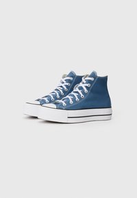 Höga sneakers i blått canvas med vita snörningar, kontrasterande svarta ränder och en strukturerad gummisul. Rundad tå och metallöglor.