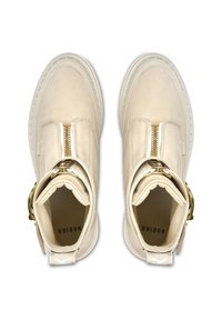 Bottines crème en cuir avec fermeture éclair à l'avant et accent en ton doré. Présente un bout arrondi et des détails cousus.