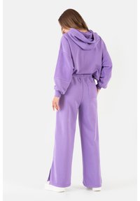 Fioletowy dres z kapturem i spodniami dresowymi wykonany z miękkiego materiału, z regulowanym kapturem oraz bocznymi rozcięciami w spodniach, z dodatkową kieszenią z tyłu.