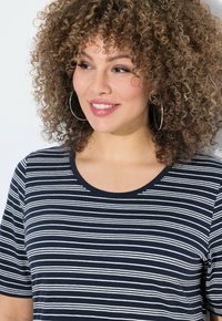 Granatowa koszulka z białymi poziomymi paskami, krótki rękaw i okrągły dekolt. Materiał bawełniany o gładkiej fakturze.