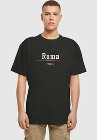 Svart bomulls T-skjorte med "Roma" i hvit tekst, med grønne og røde horisontale linjer; korte ermer; avslappet passform.