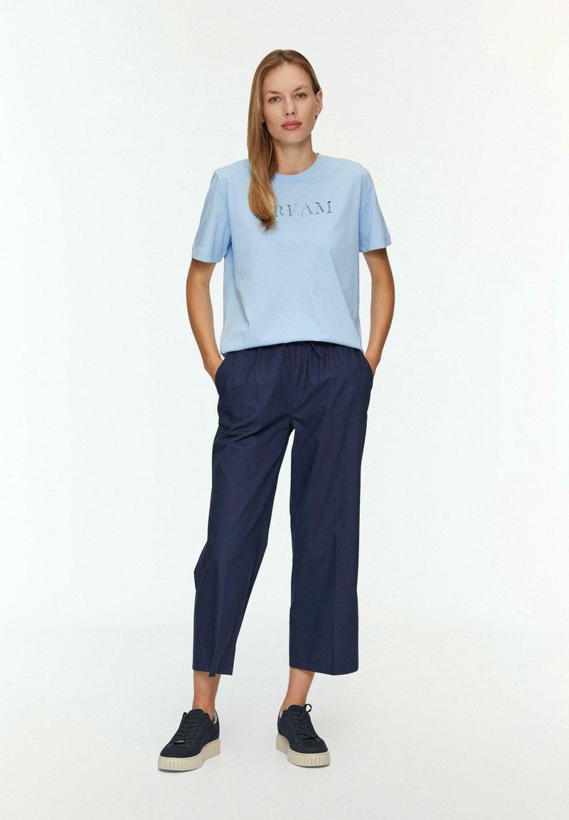 Jasnoniebieska bawełniana koszulka z napisem "DREAM"; zestawiona z granatowymi, luźnymi spodniami 3/4; czarne trampki z kremowymi podeszwami.