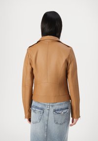 Chaqueta de cuero color marrón con un diseño ajustado, hombreras y costuras visibles. La parte trasera presenta un corte de longitud media y una textura lisa.