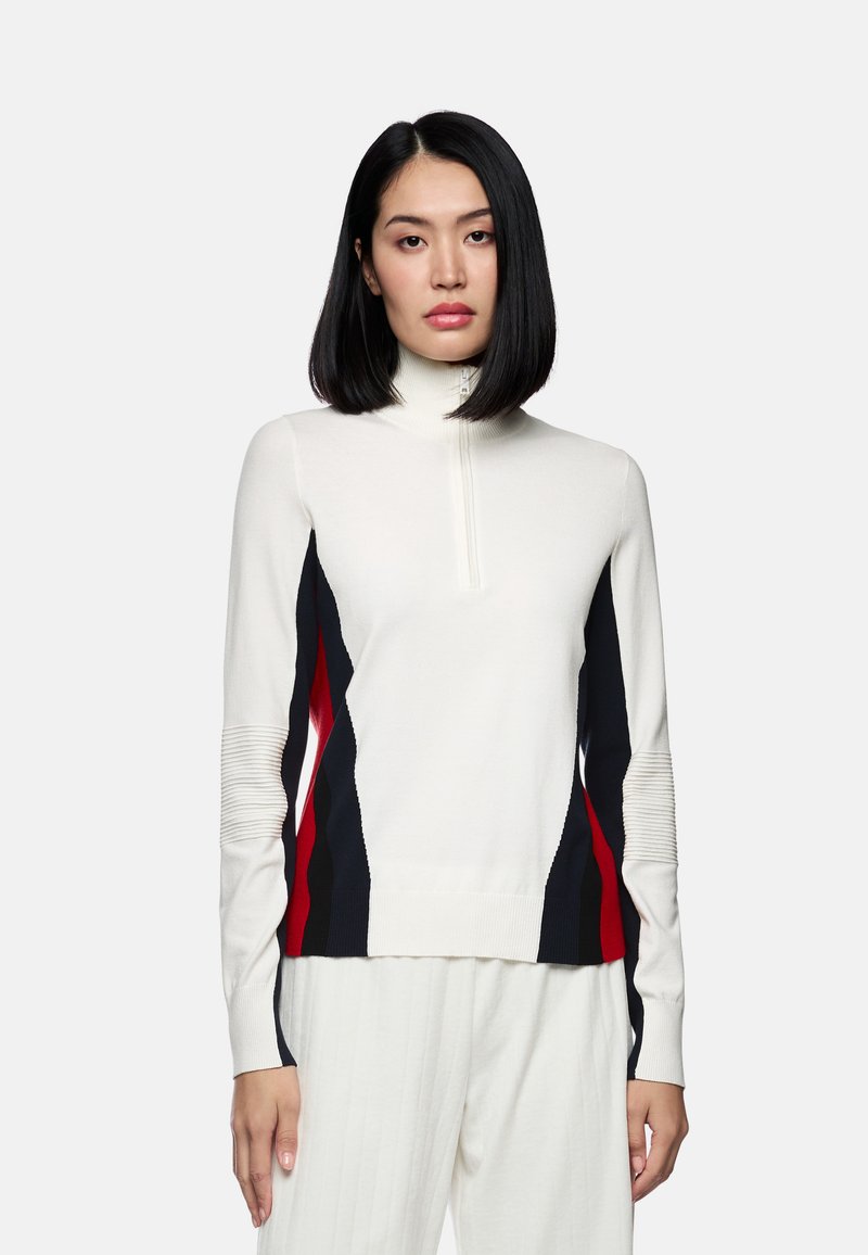 Weißer Pullover mit langen Ärmeln und hohem Kragen, der an den Seiten rote und marineblaue diagonale Streifen aufweist, eine gerippte Textur an den Ärmeln hat und mit einem Reißverschluss ausgestattet ist.