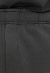 Dark gray elastic waistband with stitched detailing, soft fabric texture, and side pleats. Suitable for casual wear.