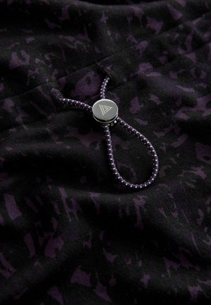 Tessuto nero con un motivo astratto viola scuro, dotato di un toggle metallico argento e di un cordoncino viola abbinato. Texture morbida.