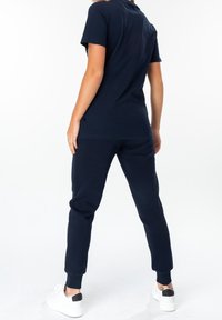 Navy blue cotton t-shirt and joggers set. T-shirt has short sleeves and a round neckline; joggers feature ribbed cuffs and side pockets.