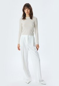 Gestreepte lange mouwen top in romig beige en wit, gecombineerd met hoge taille witte trousers, met een ontspannen pasvorm en een gladde stof textuur.