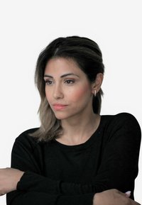 Crna majica dugih rukava, glatke teksture, s okruglim izrezom. Osoba ima svijetlosmeđu kosu s suptilnim svijetlim pramenovima, a na ušima nosi male srebrne naušnice.