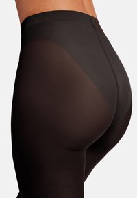 Leggings neri con un design a pannelli trasparenti. Il tessuto è liscio, elastico e aderente, evidenziando le curve del corpo. Presenta una vita alta.