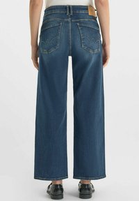 Wijdvallende blauwe denimjeans met een hoge taille, twee achterzakken en een leren label op de tailleband. Soepele textuur met een klassiek ontwerp.