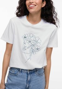 Hvid bomuld t-shirt med en blå kontur af en kvindes ansigt prydet med blomsterelementer. Standard pasform med korte ærmer.