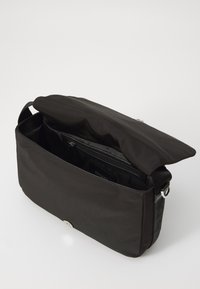 Sort nylon crossover taske med flap-top, indvendig lynlås lomme og justerbar rem, der har et elegant rektangulært design.