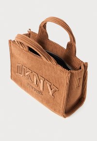 Brown corduroy handbag with DKNY logo embossed, featuring two short handles and a zip closure at the top. Interior is black.